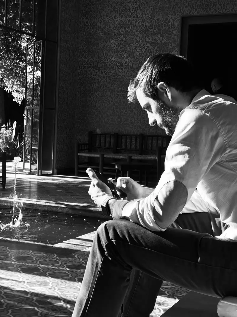 Charly Vaquero sentado mirando el móvil, fotografía en blanco y negro